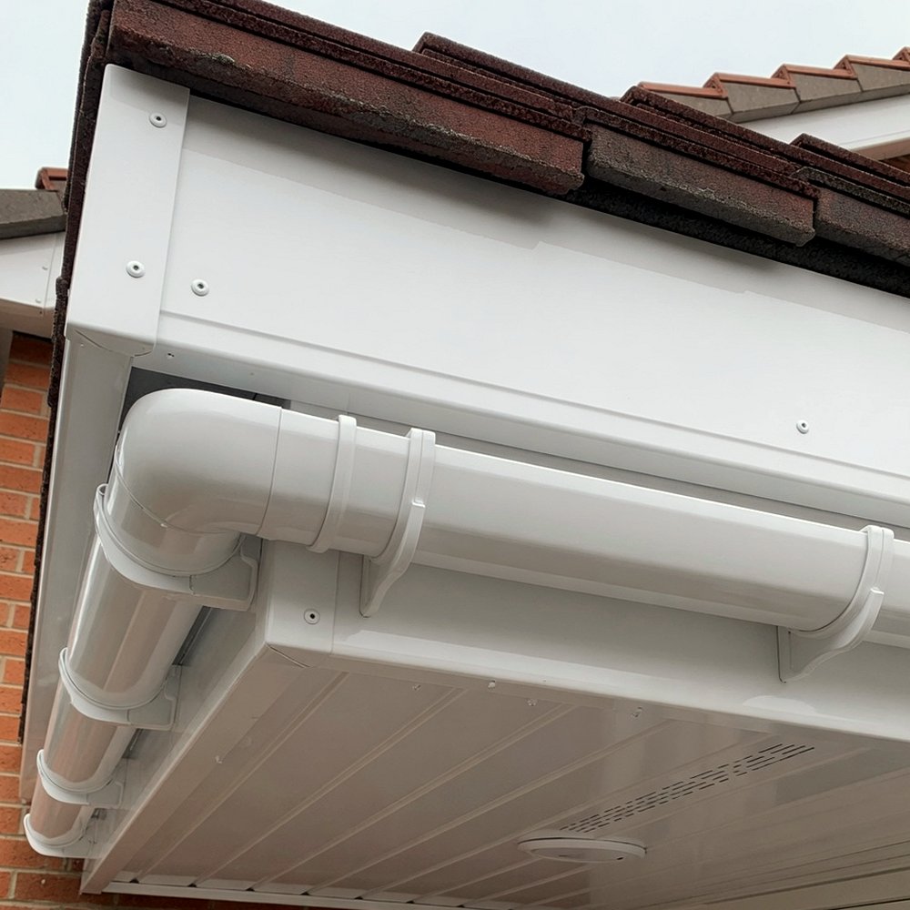 White UPVC fascia boards, soffit panels and gutter at the eaves of a tiled roof